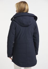 Abrigo softshell azul marino con capucha, costuras verticales y cintura ajustada. La vista trasera muestra un corte más largo y una textura suave.