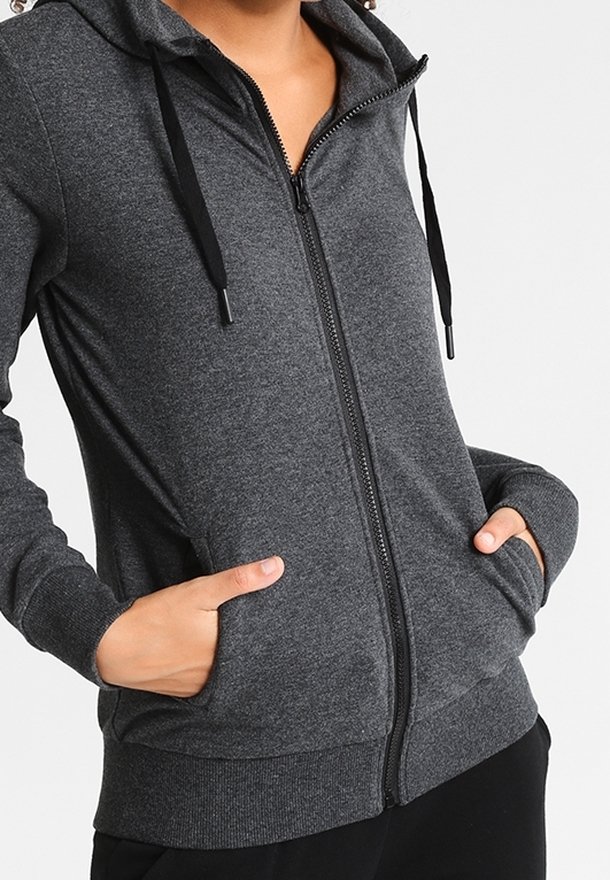 Sudadera con capucha gris con cremallera, con cordón en la capucha, bolsillos delanteros y puños acanalados. Textura suave y ajuste casual. Cremallera en la parte delantera central.