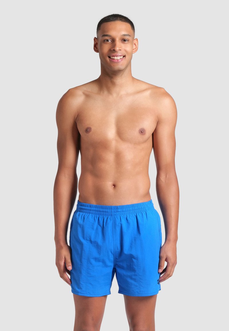 Modré plavecké šortky vyrobené z lehkého materiálu, s elastickým pasem a malým logem na boku.