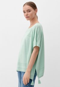 Mintgroene tuniek met korte mouwen, met kantdetails en franjes aan de zoom. Gemaakt van lichte stof, met een losse pasvorm.