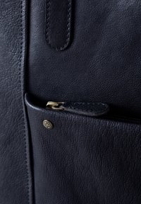 Black leather handbag featuring a textured finish, a small zipper pocket, and a gold-toned hardware accent near the zipper.
