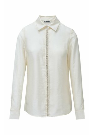 Camisa de manga larga color blanco roto con cuello clásico, con cierre frontal de botones decorado con adornos a lo largo de la costura central.