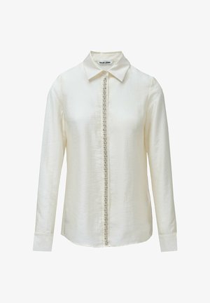 Camisa de manga larga color blanco roto con cuello clásico, con cierre frontal de botones decorado con adornos a lo largo de la costura central.