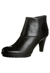 Botines de cuero negro con tacón alto, punta redonda y puño elástico. Presentan una textura suave y un diseño minimalista.