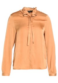 Blouse à manches longues couleur pêche avec col volanté et nœud noué au niveau de l'encolure, tissu léger et lisse, poignets à boutons.