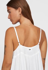 Weißes ärmelloses Kleid mit dünnen Trägern, aus strukturiertem Stoff, mit gerafftem Taillenbereich und einem kleinen metallischen Logodetail auf dem Rücken.