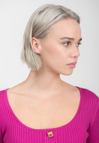 Strakke geribde top in levendig roze met een brede ronde hals, voorzien van een klein gouden vierkant accent bij de kraag. Glad textuur.