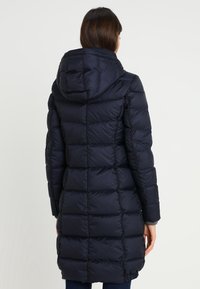 Mörkblå puffjacka med huva, med en vadderad design och långa ärmar, som når till mitten av låret med en isolerad textur.