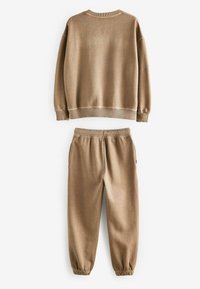 Beige sweatshirt och matchande sweatpants i mjukt tyg. Toppens har rundad halsringning och ribbade mudd; byxorna har resår i midjan.