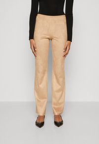 Beige suedebukser med rett snitt, med sidet detaljer og en glatt tekstur. Kombinert med spisse svarte hæler.