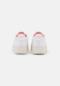 White ASICS sneakers with a smooth leather texture, pink accents on the collar and logo, and a thick beige rubber sole.