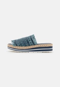 Vävt teal slide sandal med fransdetalj, mellansula av naturliga fibrer och en randig gummisula för grepp. Har en öppen bakdesign.
