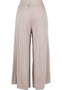 Pantalon beige à jambes larges avec taille élastique, tissu lisse et ourlet à la cheville, vu de dos.