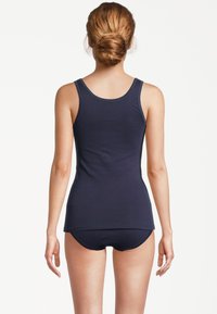 Canotta in cotone blu navy con collo rotondo e spalline sottili, abbinata a pantaloncini a vita bassa coordinati, tessuto strutturato, design aderente.