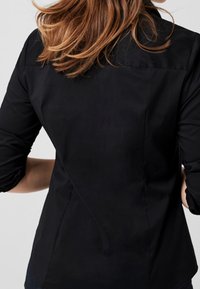Schwarze taillierte Bluse mit langen Ärmeln und einer glatten Textur. Ein bemerkenswertes Detail sind die maßgeschneiderten Nähte auf der Rückseite.