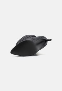 Sandal com ponta afilada, salto stiletto preto, revestido de um tecido texturizado e sola lisa. Apresenta um fecho de correr ao longo do lado e uma silhueta elegante.