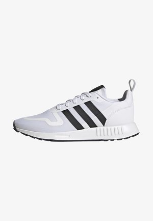 Baskets blanches de sport avec des bandes noires, des lacets blancs et une languette au talon, vues de côté sur fond blanc.