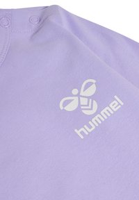 Ljust lila bomullsplagg med rundad halsringning, med två tryckknappar och en vit "hummel"-logotyp med ett bi-design framtill.