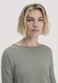 Hellgrüner, weicher Strickpullover mit weitem Ausschnitt und locker sitzenden Ärmeln. Glatte Textur, einfaches Design, geeignet für die Freizeit.