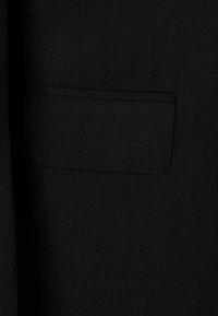 Schwarzer Blazerstoff mit feiner Struktur, ausgestattet mit einer Paspeltasche auf der linken Seite. Einfaches Design mit klaren Linien und ohne sichtbare Beschläge.