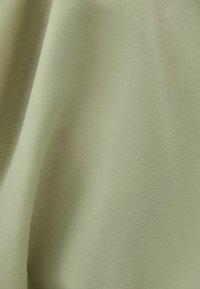 Jasnozielony materiał o gładkiej, lekko błyszczącej fakturze, z delikatnymi różnicami w odcieniach i bez widocznych wzorów ani akcentów.