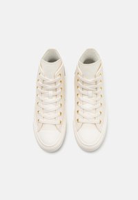 Hoge witte sneakers van soepel leer, met gouden oogjes, ronde neuskappen en textuurzolen in een contrasterende kleur.