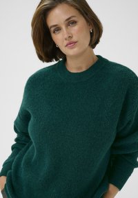 Türkiser gestrickter Pullover mit strukturierter Oberfläche, Rundhalsausschnitt und langen Ärmeln, mit einem lockeren Schnitt und ribbeligen Bündchen.
