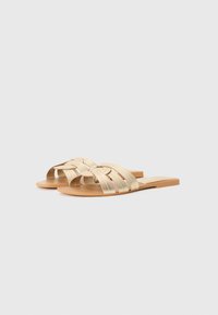 Sandalias deslizantes de oro trenzado con suela plana, que presentan un diseño de tira de múltiples hilos y una textura suave para mayor comodidad.