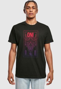 Sort bomulds T-shirt med et grafiktryk af en oni-maske i rød og lilla, med fed tekst ovenfor og japanske tegn nedenfor designet.