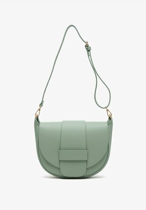 Beżowy, oversize'owy sweter z krótkimi rękawami, zestawiony z niebieskimi dżinsami i jasnozieloną torebką na ramię. Stylizację dopełniają espadryle.