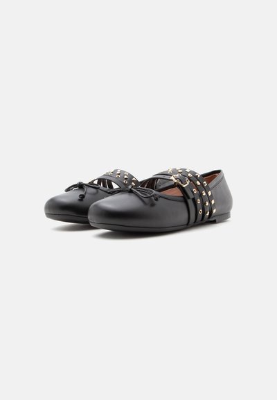 Zapatos de ballet planos negros con lazo en la parte delantera y dos tiras con tachuelas cruzando la parte superior, mostrados sobre un fondo blanco.