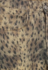 Denim tkanina z leopardjim vzorom, z bežnim podlagom in črnimi pikami, z podrobnim šivanjem in sprednjim žepom v bližini pasu.