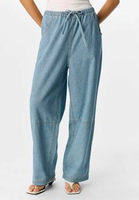 Pantaloni in denim azzurro chiaro a gamba larga con vita elastica e cordoncino, dotati di tasche frontali e dettagli di cucitura a contrasto.