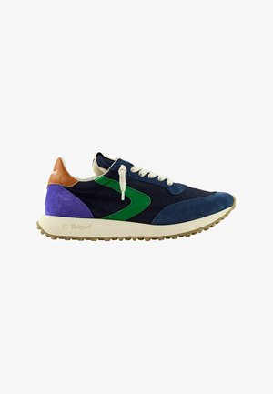Scarpa da ginnastica blu navy con design laterale verde, lacci bianchi, tacco viola, patch in pelle marrone alla caviglia e suola beige con motivo battistrada.