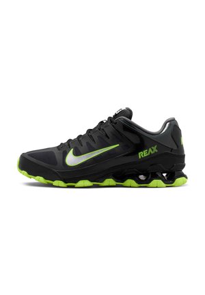 Zwart-groene Nike hardloopschoen met groene zool, groen Swoosh-logo en "REAX" tekst aan de zijkant, gezien van links profiel.