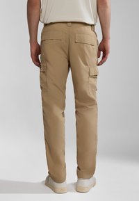 Beige cargo bukser med flere sidelommer og bagflapper, lavet af letvægtsstof, med lige ben og let glans.
