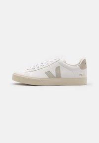 Hvit skinnsneaker med beige detaljer, flat gummisåle, rund tå og kontrasterende logo på siden og baksiden. Snøresystem.