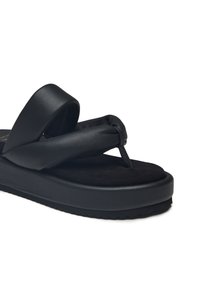 Sandalo flip-flop nero con suola spessa e ammortizzata, design con fascetta attorcigliata e materiale sintetico liscio con fondo in suede morbido.