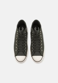 Para czarnych wysokich sneakersów z białymi gumowymi czubkami i czarnymi sznurówkami, widocznych z góry na białym tle.