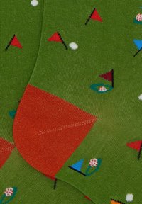 Calzini verdi con un motivo ripetuto di bandiere da golf, palle da golf e fiori, con una punta e dettagli di cucitura rossi in contrasto.