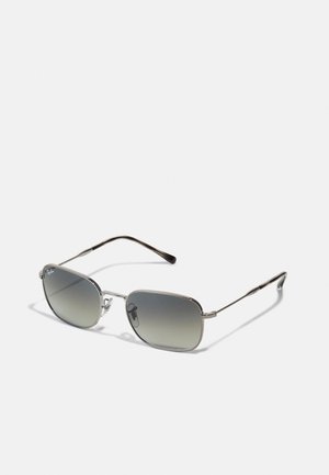 Occhiali da sole metallici argentati con lenti a gradiente argento, lenti rettangolari e steli sottili con una leggera curvatura. Design minimalista.
