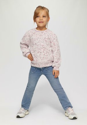 Pull en tricot rose clair avec un motif texturé, associé à un jean bleu. Le mannequin porte des chaussures de sport blanches et grises. Fond neutre.