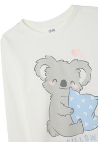 Weißes Baumwollhemd mit langen Ärmeln, auf dem ein Cartoon-Koala abgebildet ist, der ein blaues Kissen mit weißen Herzmustern hält. "OVS"-Etikett am Kragen.