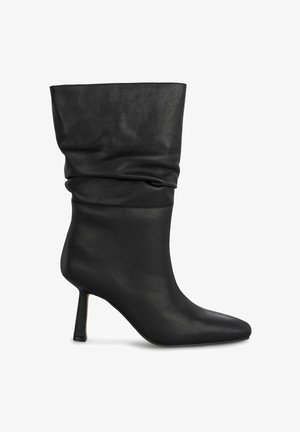 Bottine en cuir noir avec un design flasque, un bout pointu et un talon aiguille fin. Texture lisse avec des accents minimalistes.