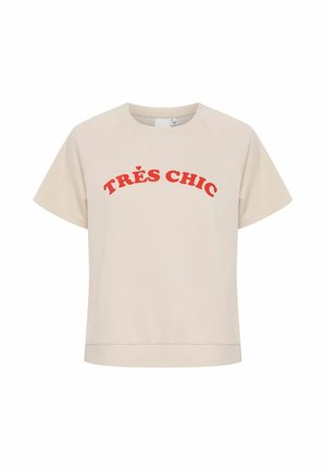 Bežs īsās piedurknes T-krekls ar noapaļotu kakla izgriezumu un sarkanu tekstu "TRÈS CHIC" frontē. Mīksta auduma, nedaudz brīva piegriezuma.