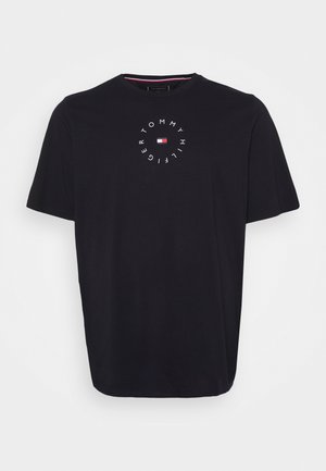 T-shirt noir à manches courtes avec col rond, portant le texte circulaire "Tommy Hilfiger" et un petit logo rouge, blanc et bleu au centre de la poitrine.