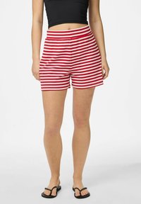 Sarkanie un balti svītraini šorti ar elastīgu jostasvietu, izgatavoti no mīksta auduma, ar brīvu piegriezumu un vidēja garuma līdz augšstilbiem.