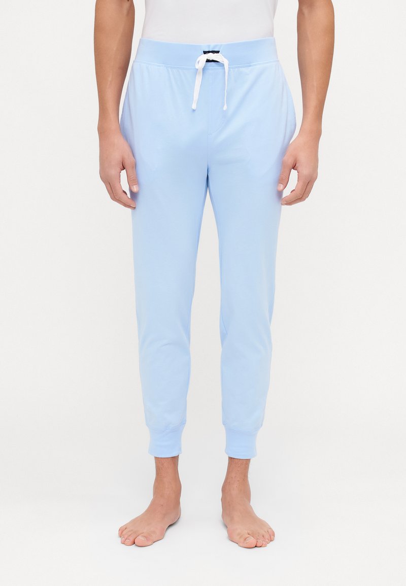 Lyseblå joggebukser laget av mykt stoff, med en snøring i livet, tapered ben-design og ribbestrikkede mansjetter ved anklene.