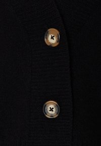 Cárdigan negro de punto con dos grandes botones redondos y marmoleados. Tejido texturizado con detalles de costura visibles.