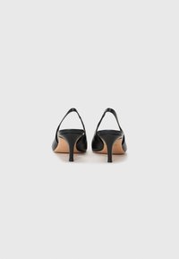 Tacchi slingback in pelle nera con punta affusolata, tacco sottile e texture liscia. Design minimalista con retro scoperto per un'eleganza aggiuntiva.